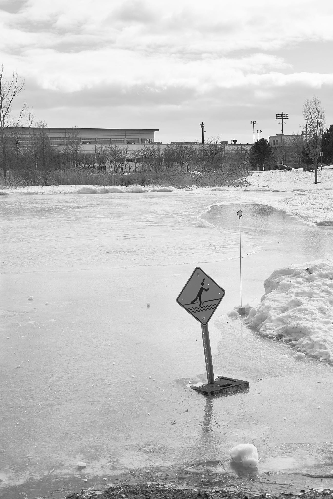 A sign on the pond in Parc Jarry warning about dangerous ice with the ice itself in the background