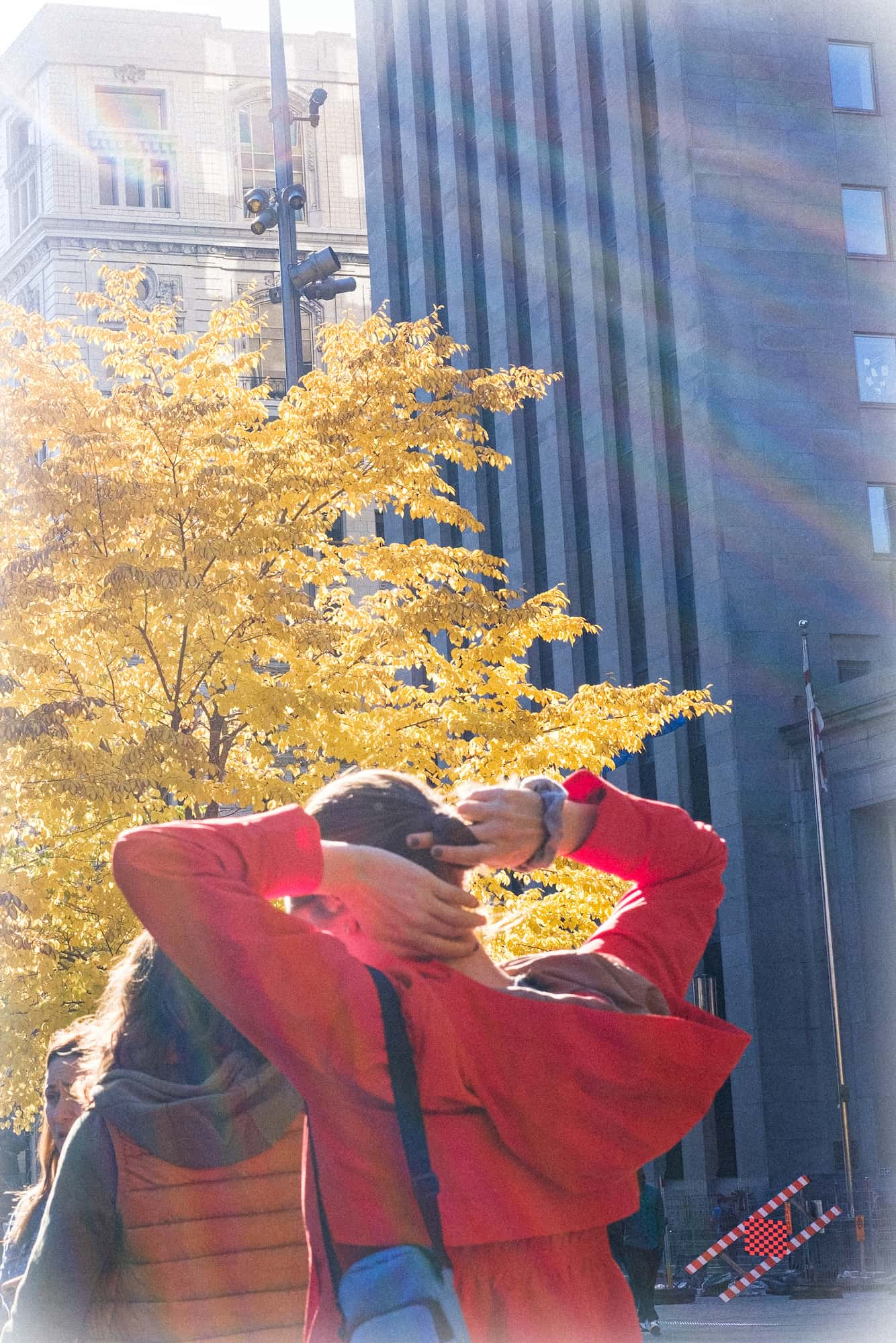 People walk past autumn-clad trees in the city centre